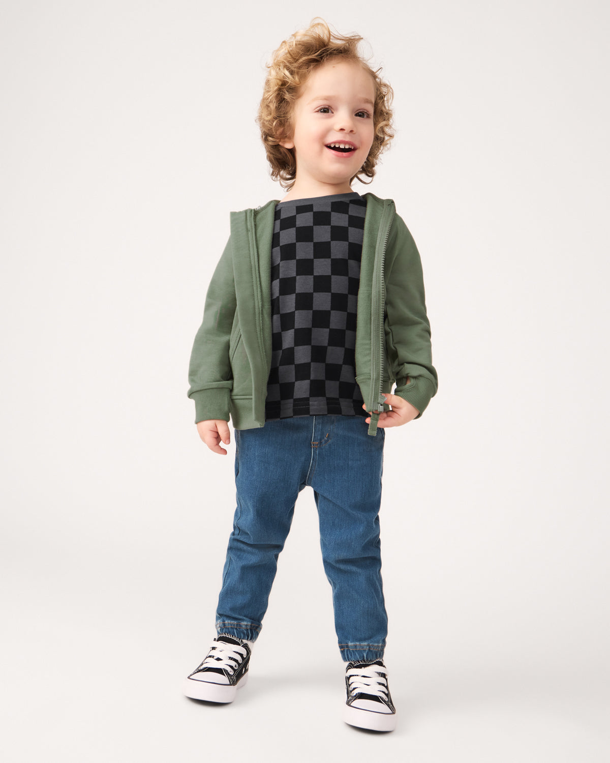 Standing boy wearing the Moss Zip Hoodie layered over a monochrome check tee