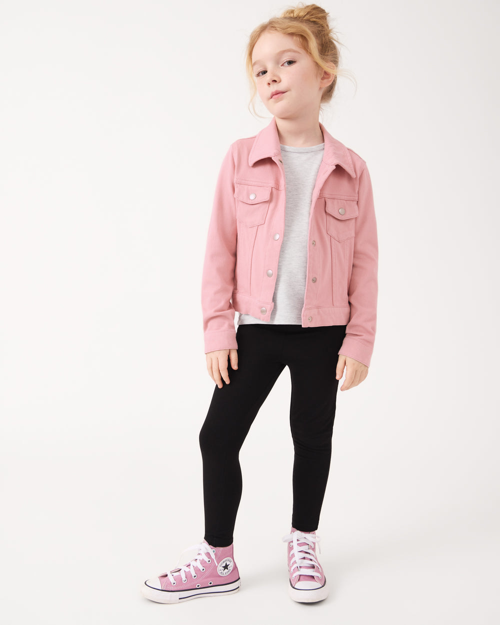 Girl wearing the Mauve Blush Denim Trucker Jacket with black leggings and pink Converse