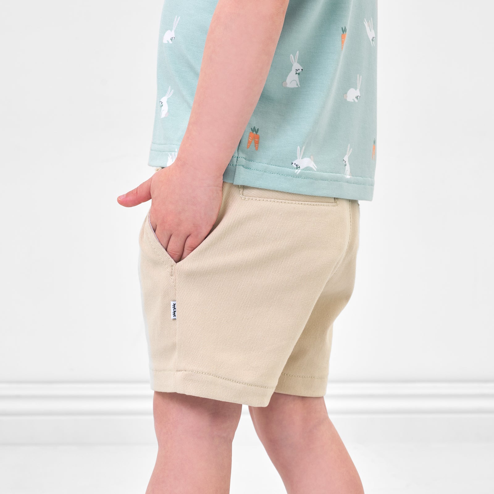 Close up side view image of a child wearing Light Khaki chino shorts