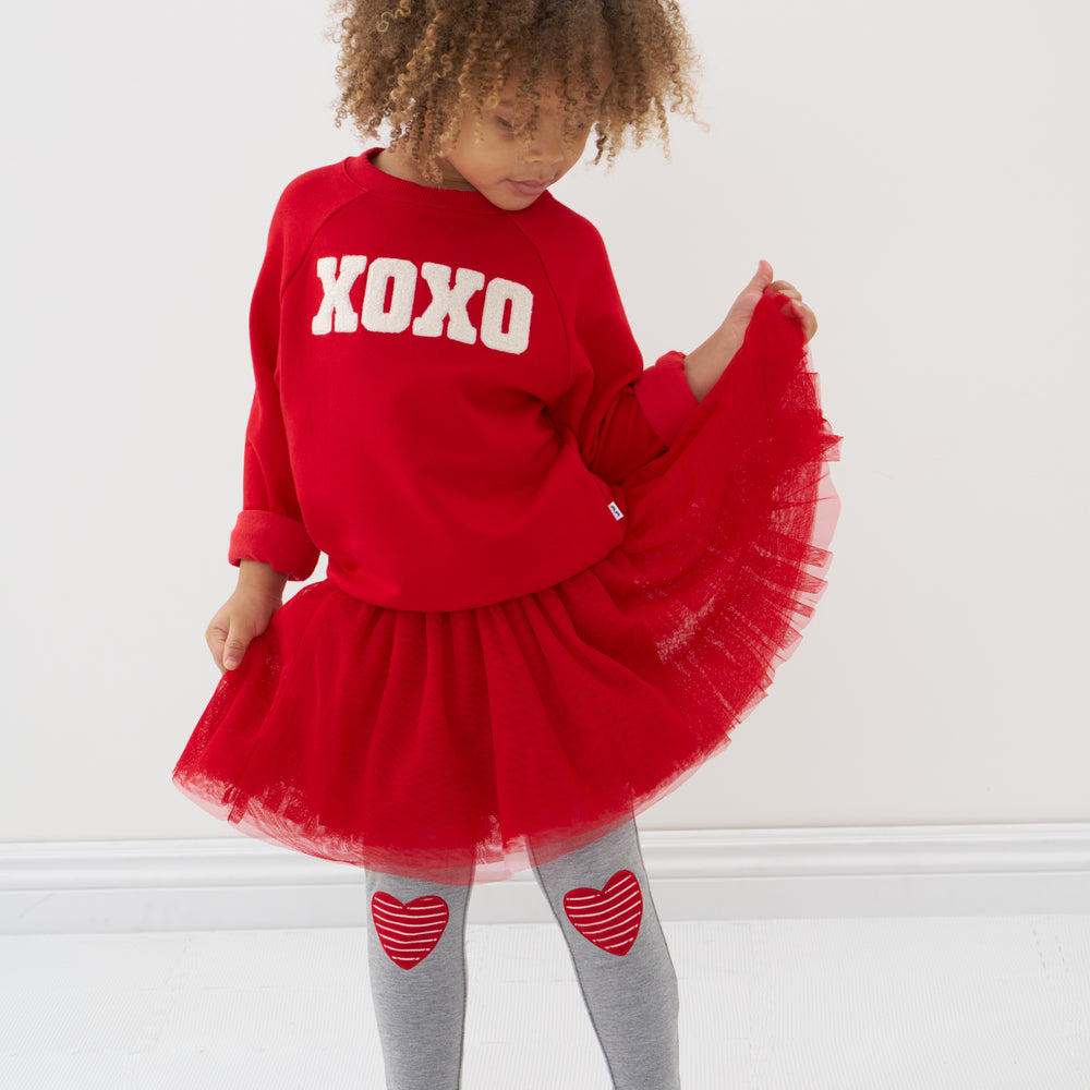 Click to see full screen - Child wearing a Candy Red tutu skirt with matching crewneck sweatshirt and coordinating heart patch leggings