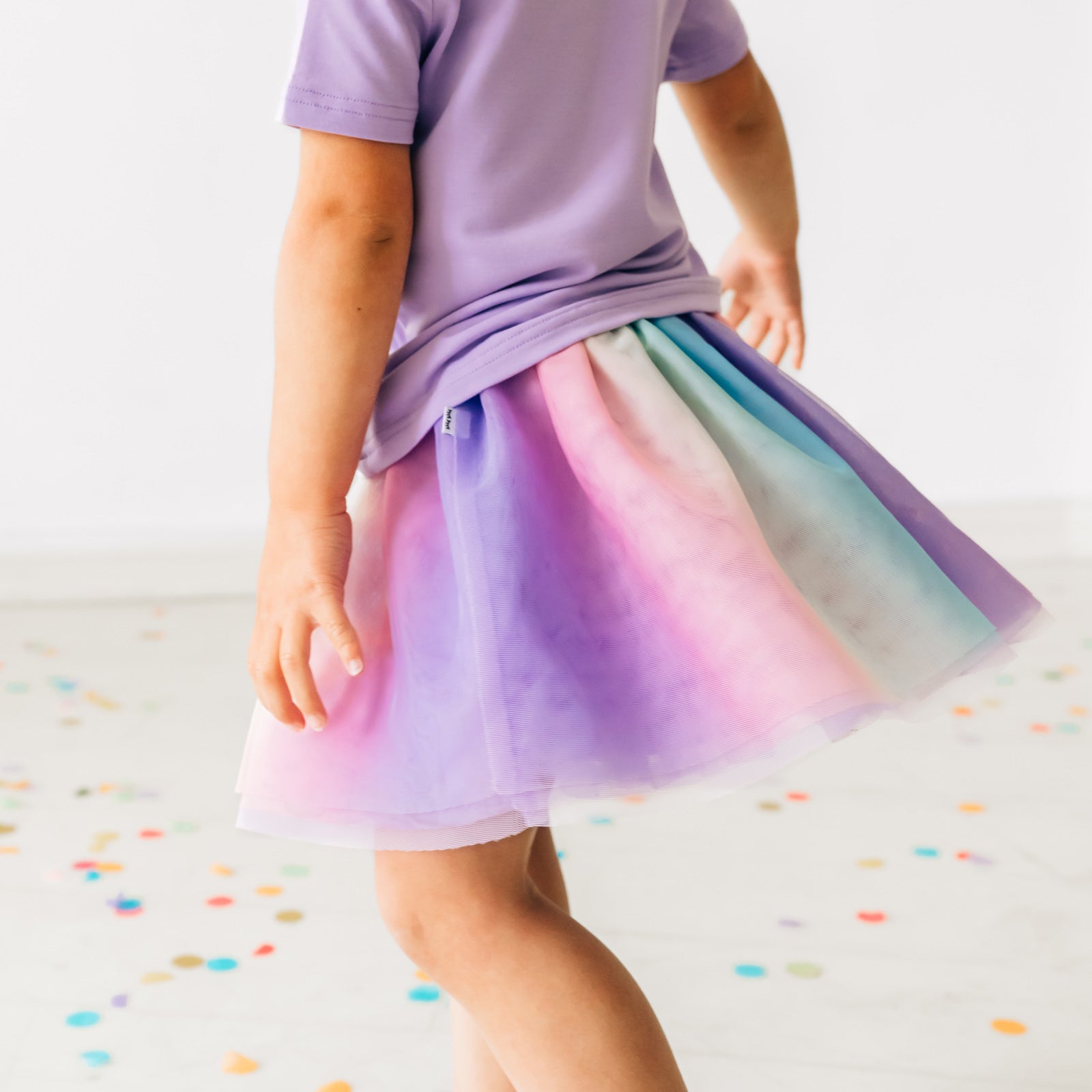 Close up image of a child wearing a rainbow tutu skirt