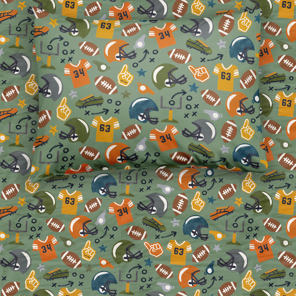 Close-up of football-themed bedding set, featuring a pillow and sheet adorned with illustrations of jerseys, helmets, footballs, and sports icons on a green background.