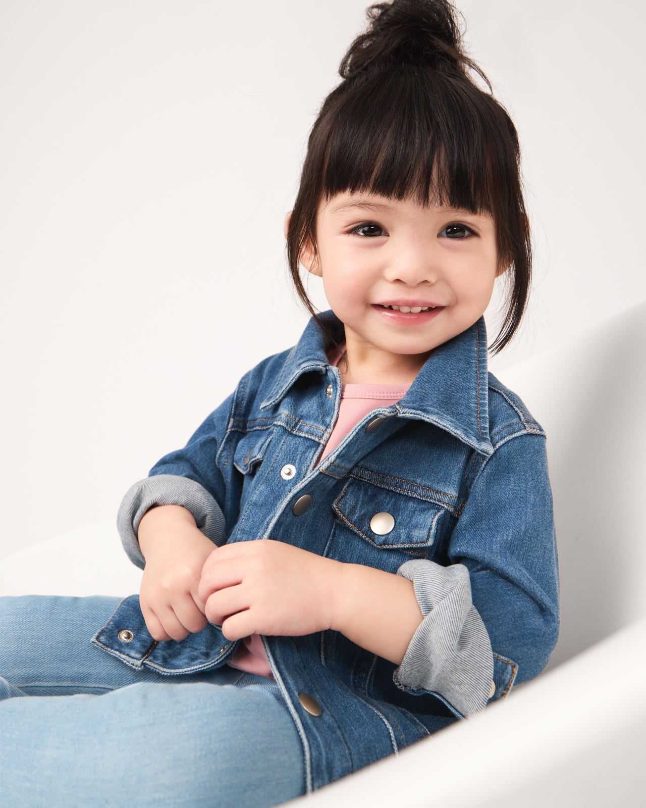 Girl wearing the Midwash Blue Denim Trucker Jacket with the sleeves rolled up 