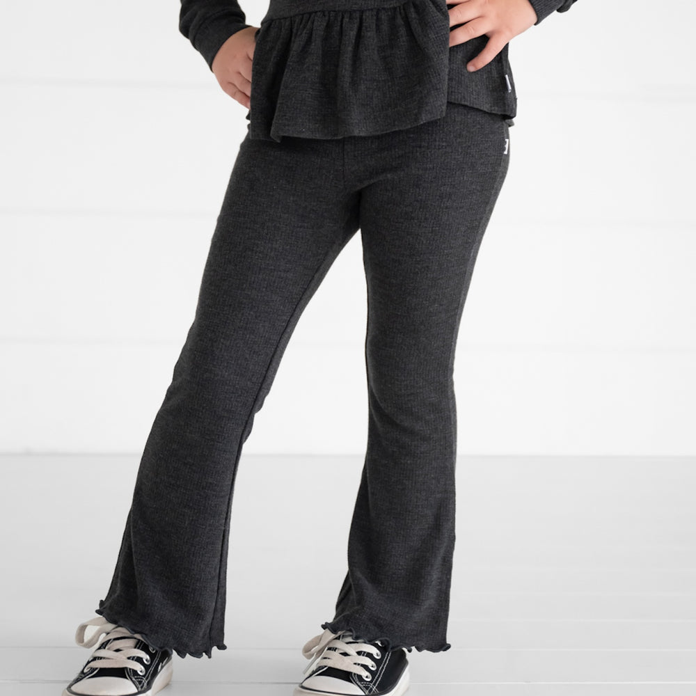 Close up image of a child wearing a Heather Black Waffle Flare Pant and Peplum Hooded Tee