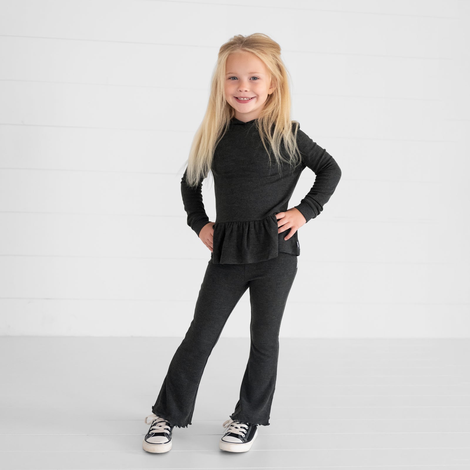 Image of a child wearing a Heather Black Waffle Flare Pant and Peplum Hooded Tee