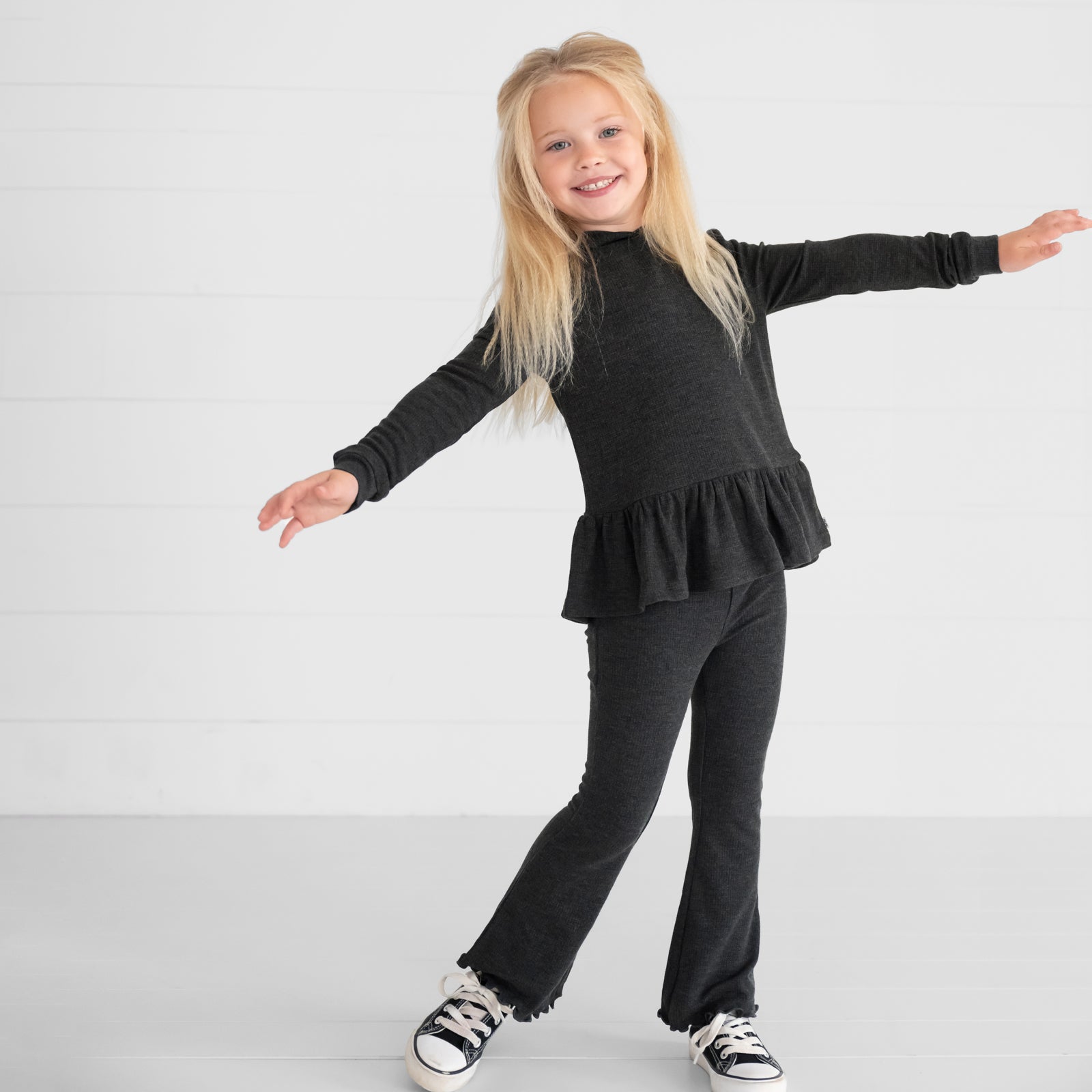 Image of a child wearing a Heather Black Waffle Peplum Hooded Tee and Waffle Flare Pant