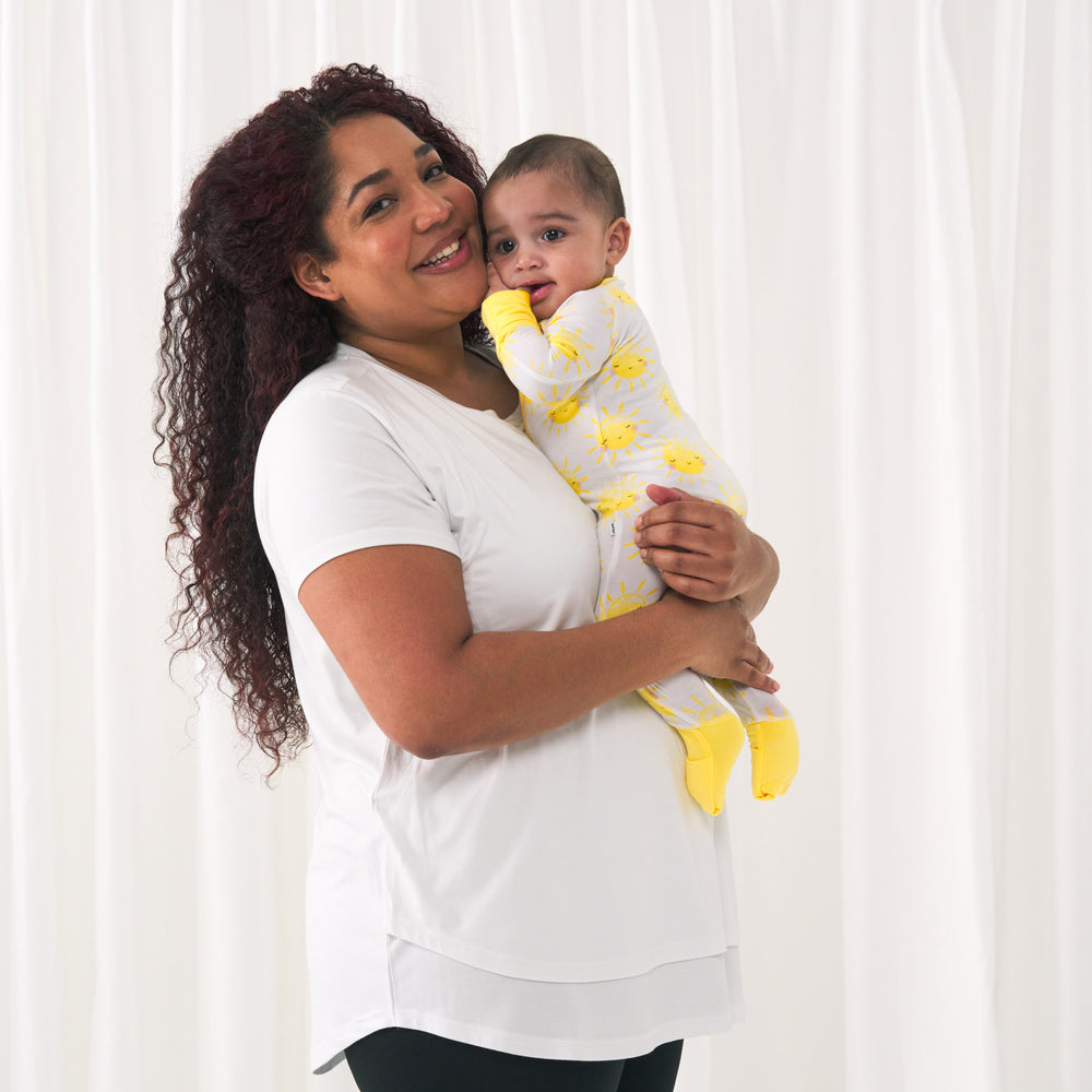 woman wearing a Bright White women's nursing top holding up her child wearing a Sunshine zippy