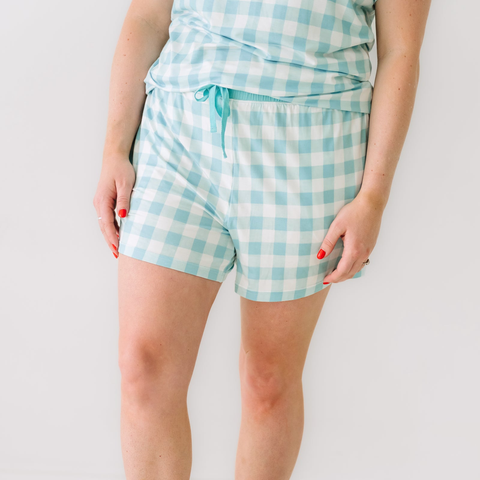 Close up image of a woman wearing Aqua Gingham pajama shorts showing off the drawstring