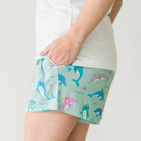 Close up side view image of a woman wearing Dolphin Dance women's pajama shorts and coordinating top