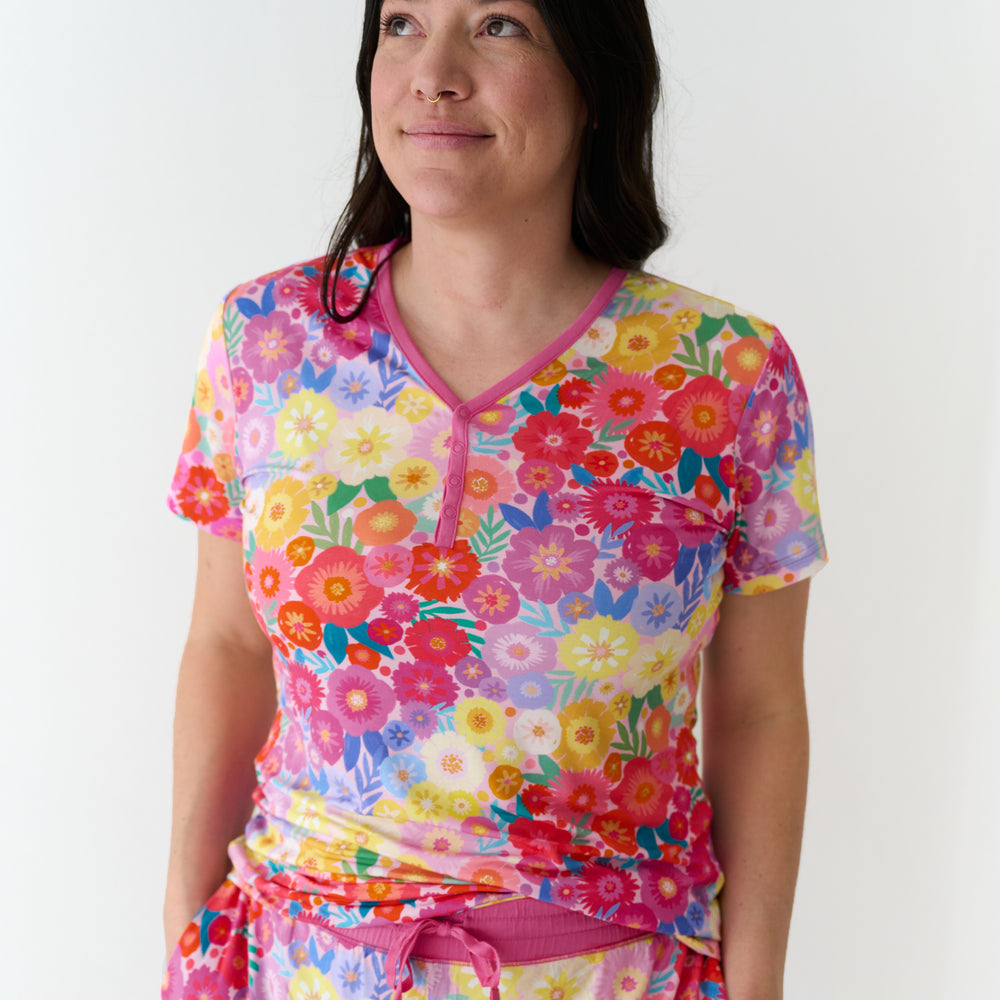 Close up image of a woman wearing Rainbow Blooms women's short sleeve pajama top and matching pajama pants