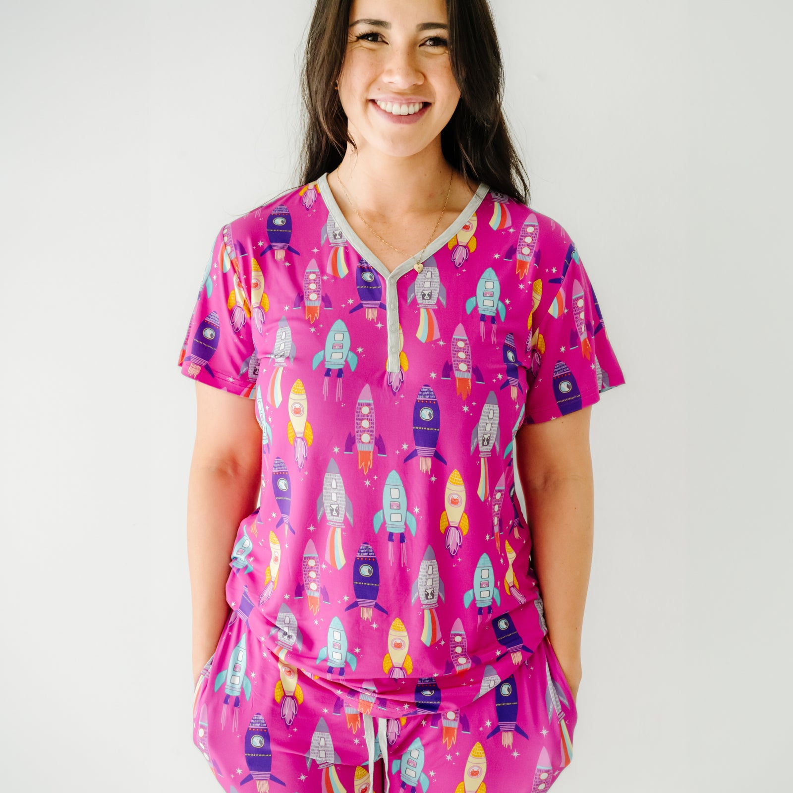Close up image of a woman wearing a women's Pink Space Explorer short sleeve pajama top and matching women's pajama pants