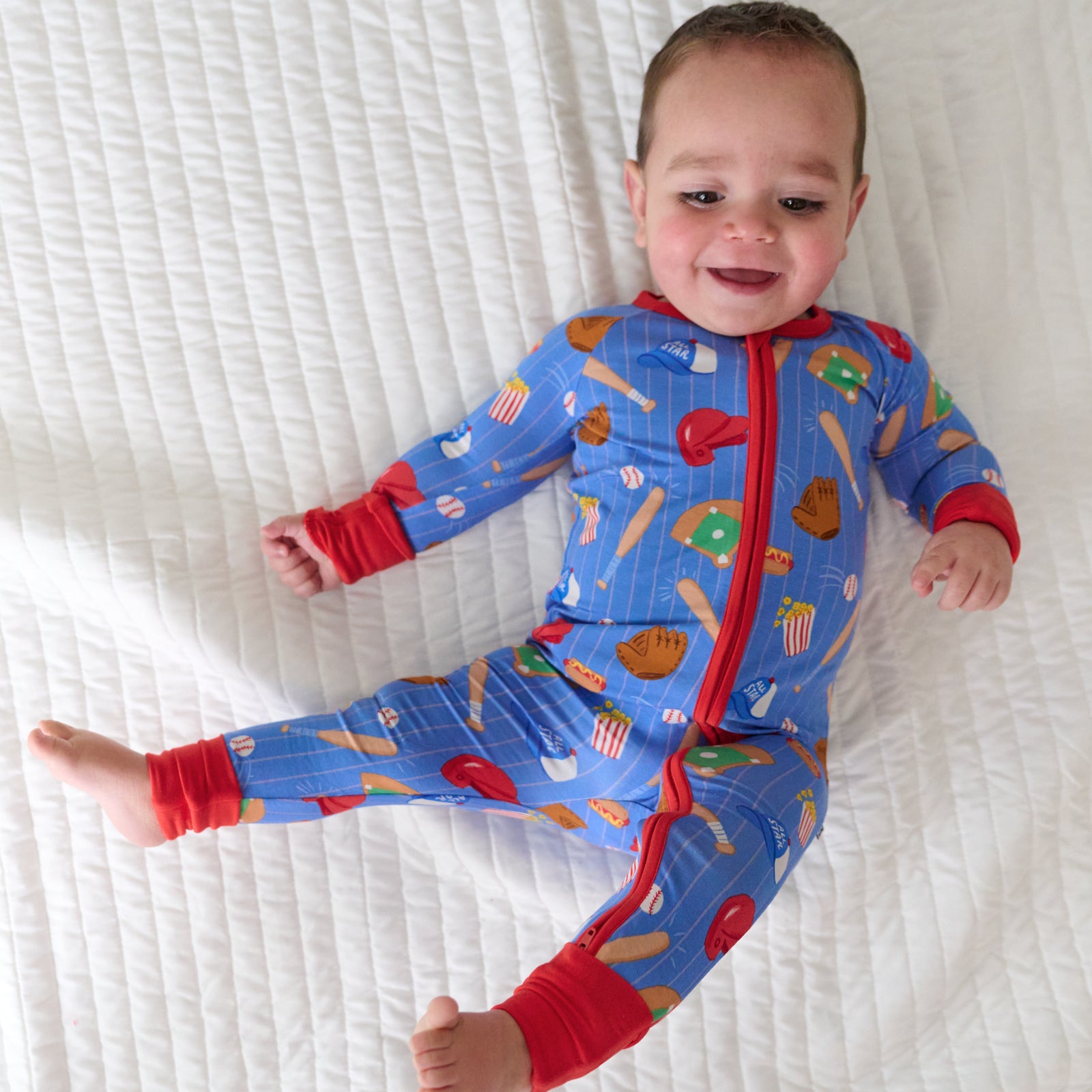 Child laying on a bed wearing a Blue All Stars zippy