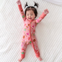 Child laying on a bed wearing a Pink All Stars zippy
