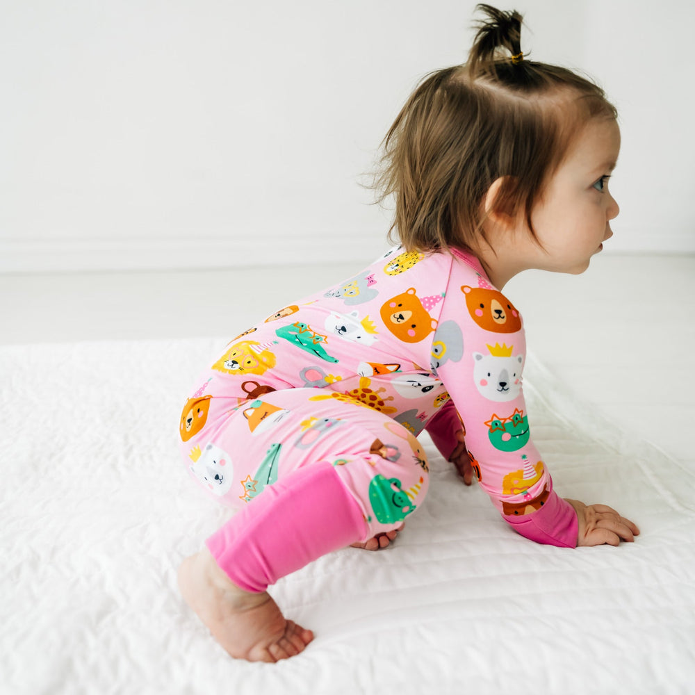 Child crawling on a bed wearing a Pink Party Pals zippy