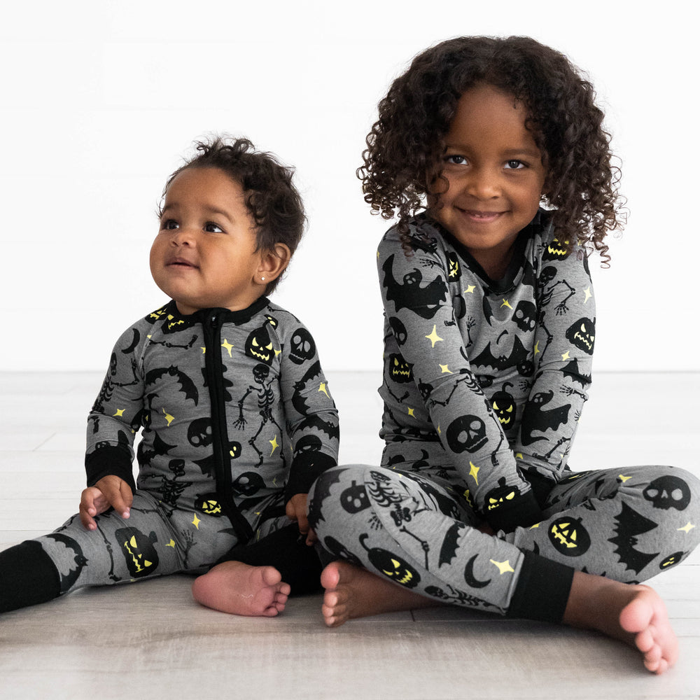 Baby on the left wearing the Gray Glowing Ghouls Zippy and girl on the right is Gray Glowing Ghouls Two-piece Pajama Set