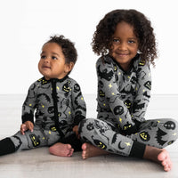 Baby on the left wearing the Gray Glowing Ghouls Zippy and girl on the right is Gray Glowing Ghouls Two-piece Pajama Set