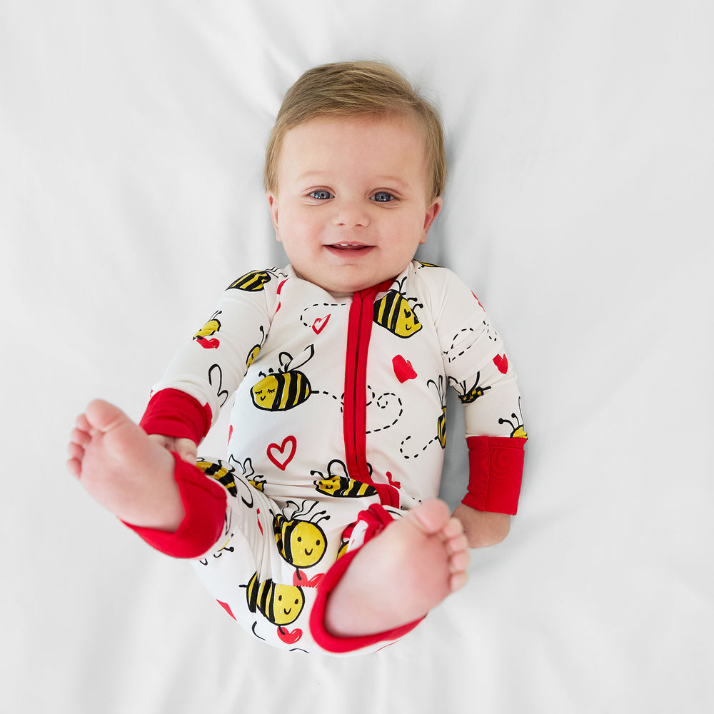 Image of a child laying on a bed wearing a Bee Mine zippy