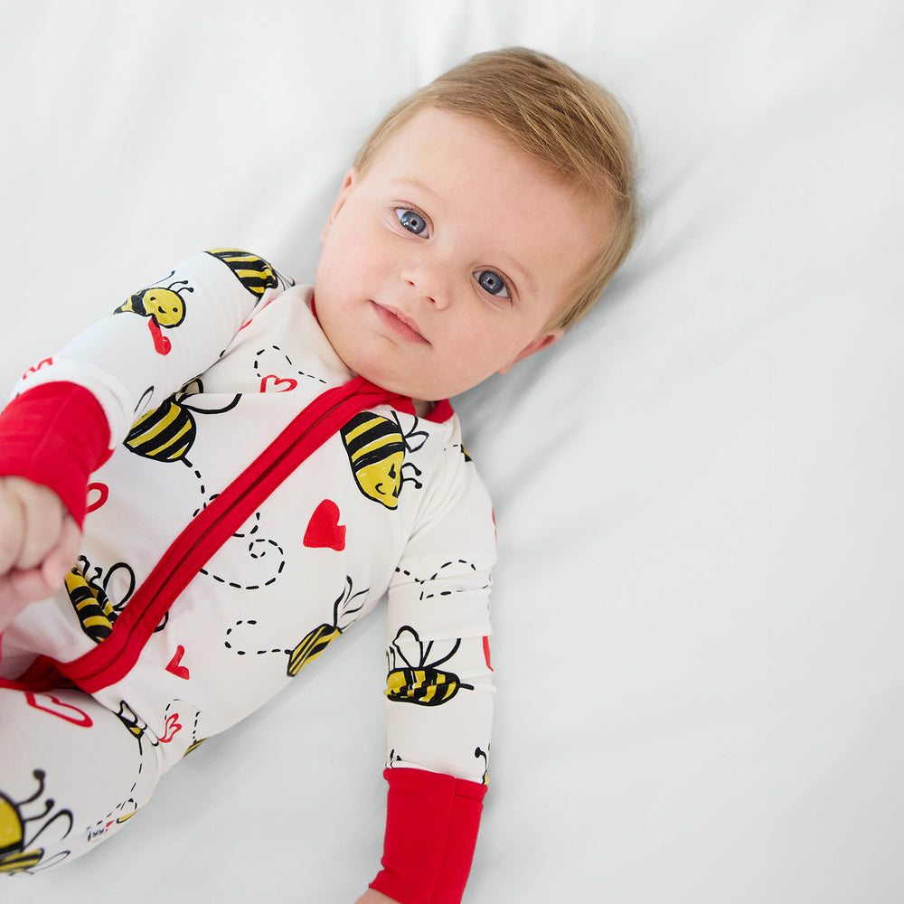 Close up image of a child laying on a bed wearing a Bee Mine Zippy