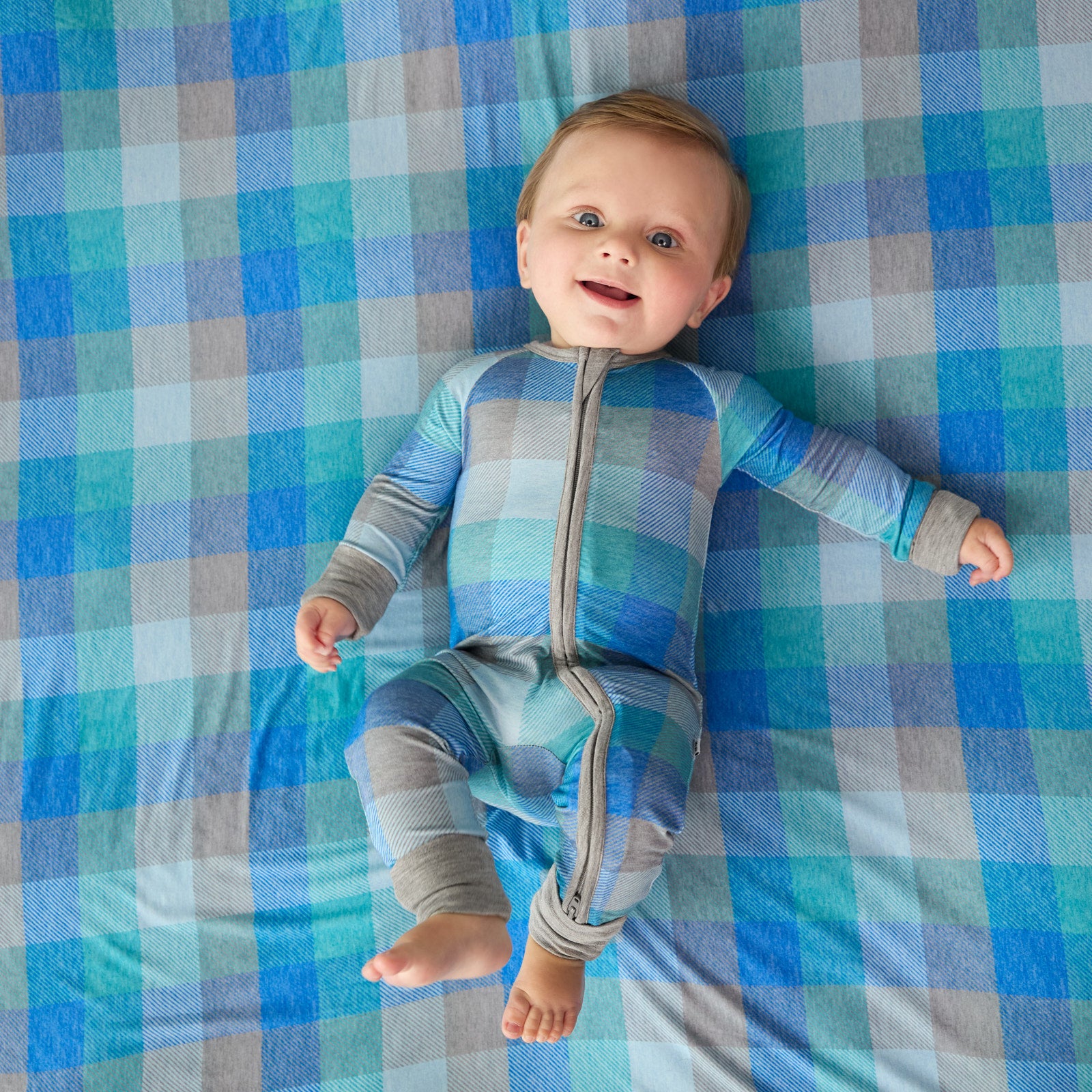 child laying on an Arctic Plaid blanket wearing and Arctic Plaid zippy