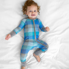 Child laying on a bed wearing an Arctic Plaid zippy