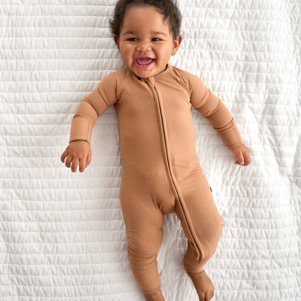 Top view image of baby laying down while wearing the Caramel Ribbed Zippy