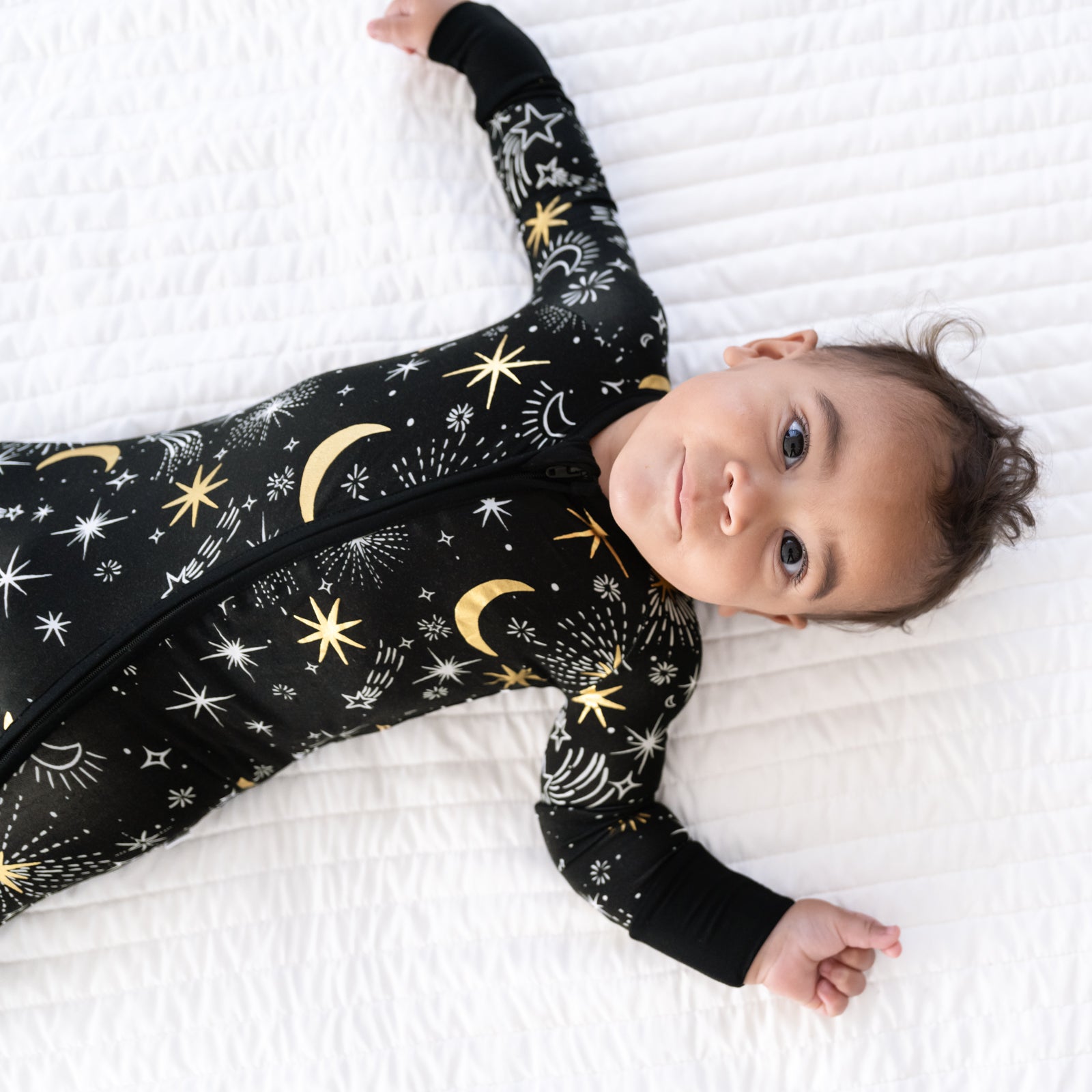 image of a child laying on a bed wearing a Celebration Stars zippy