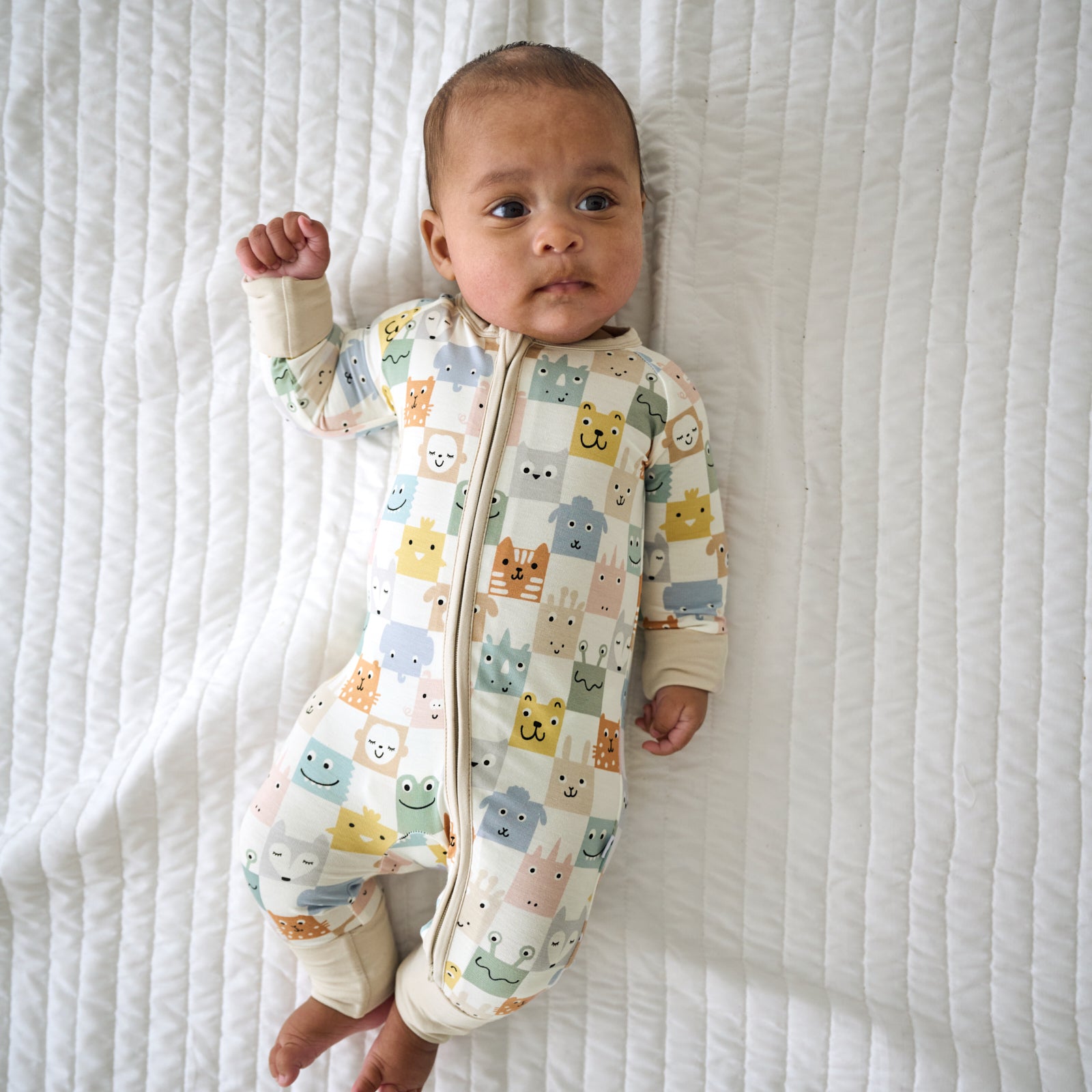 Child laying on a blanket wearing a Check Mates zippy