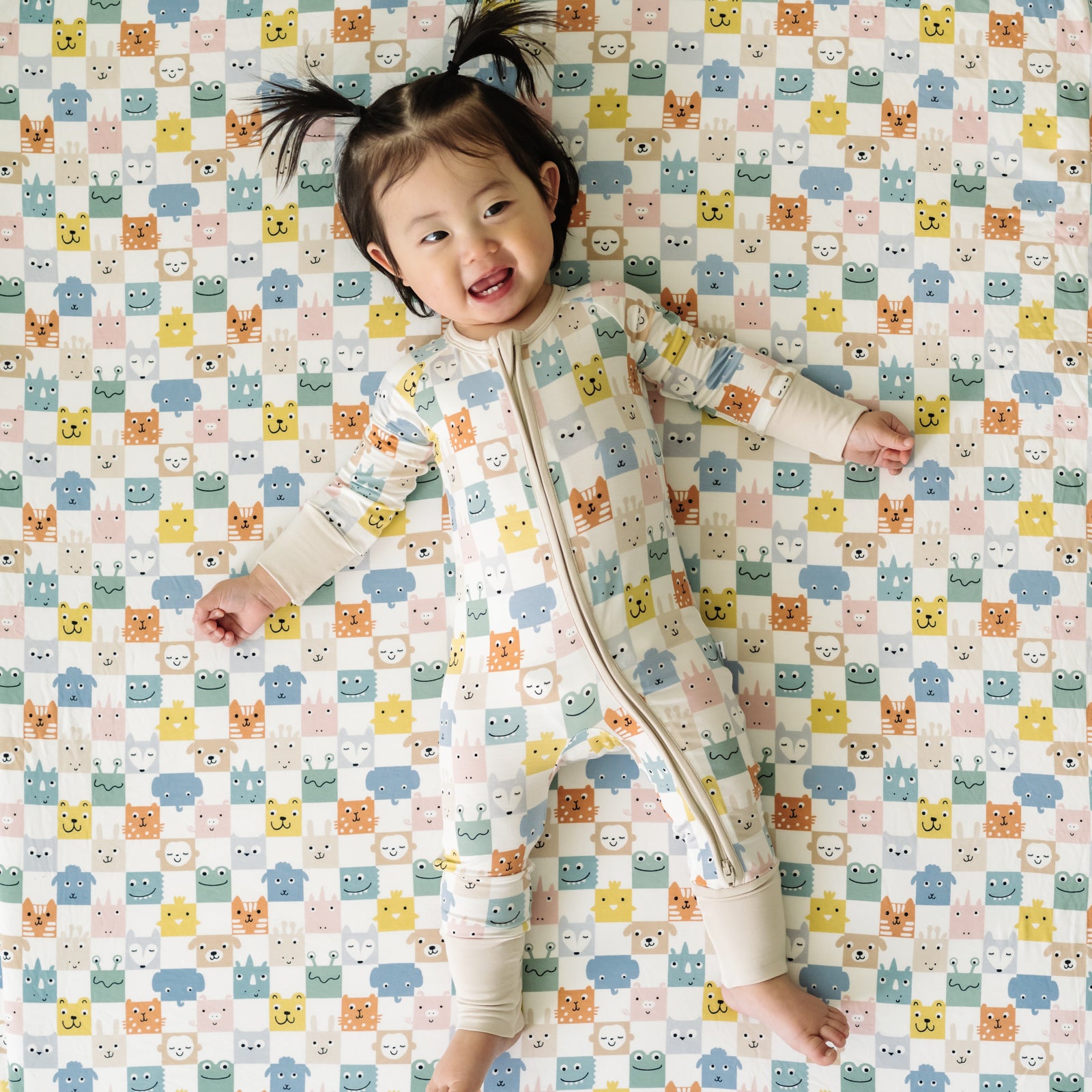 Child wearing a Check Mates zippy laying on a matching Check Mates large cloud blanket