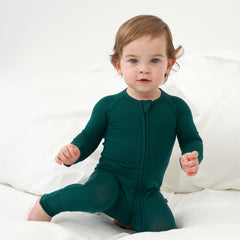 Baby kneeling on white bed while wearing the Emerald Zippy