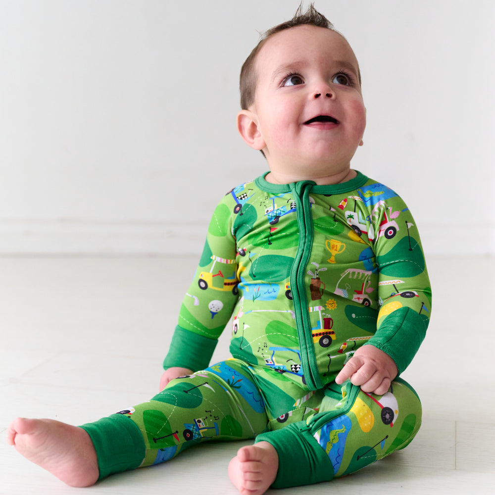 Child sitting on the ground wearing a Fairway Fun zippy