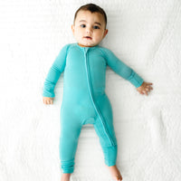 Child laying on a bed wearing a Glacier Turquoise zippy