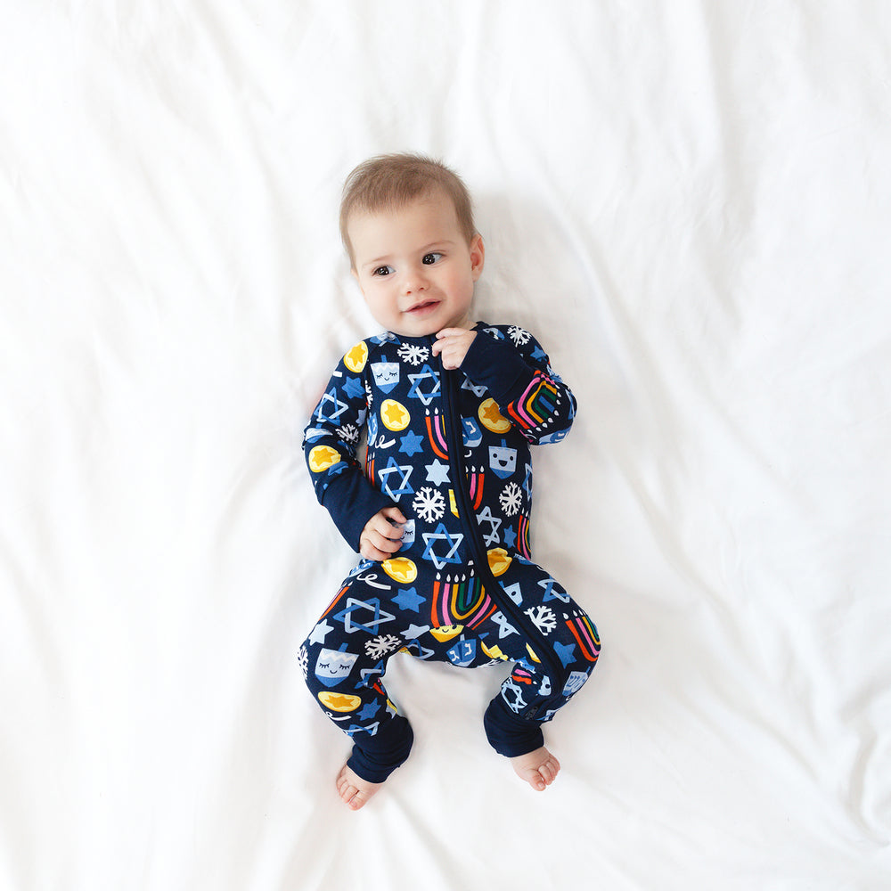 Child laying on a blanket wearing a Playful Dreidels Zippy