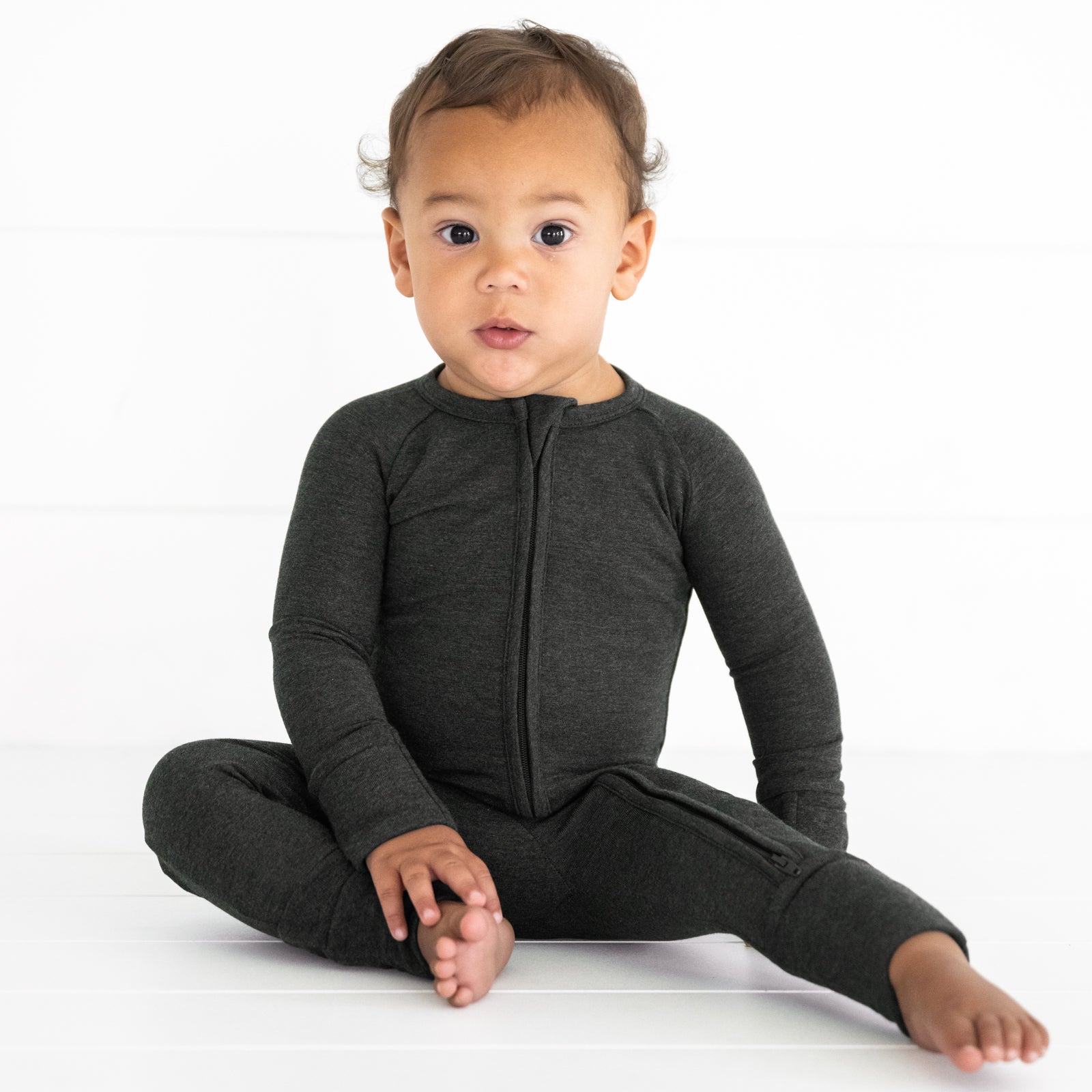 Child sitting wearing a Cozy Heather Black zippy