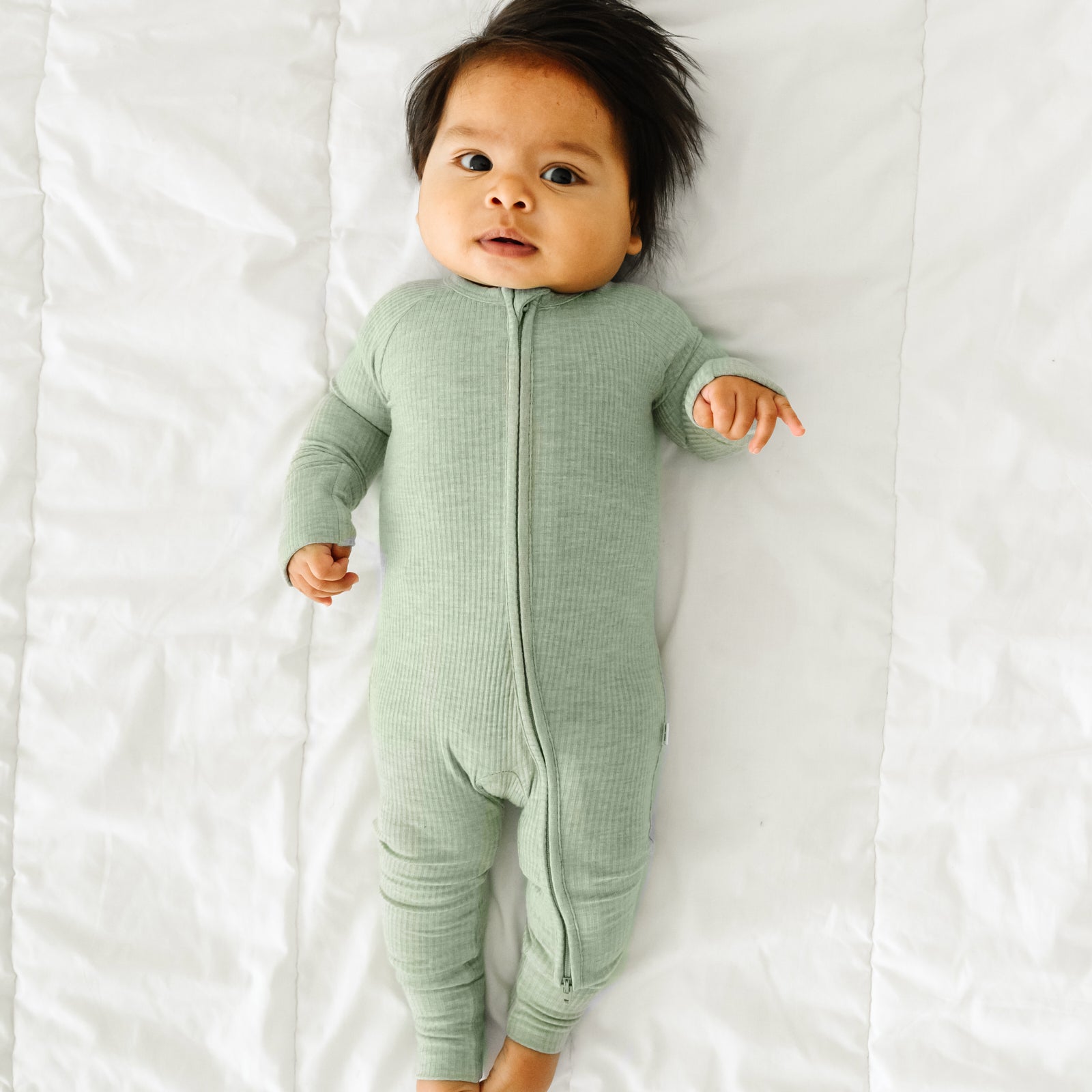 Alternate image of a child laying on a bed wearing a Heather Sage Ribbed zippy