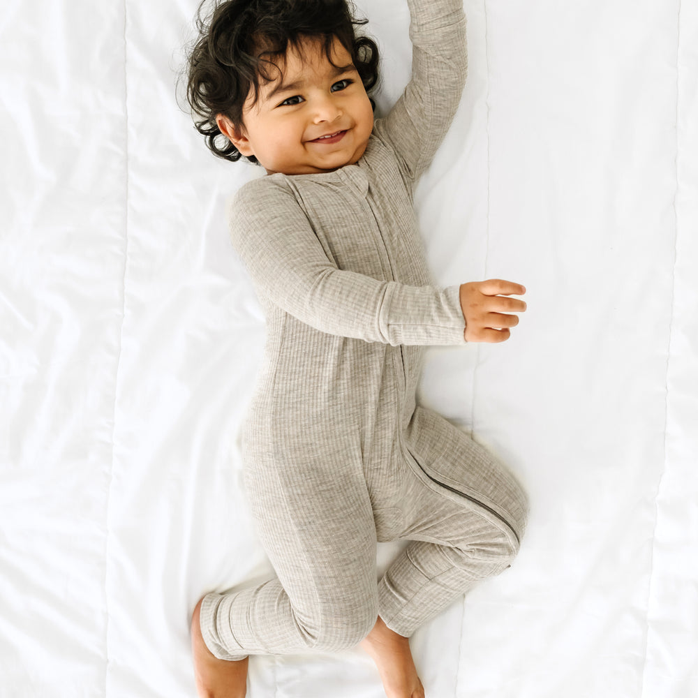 Child laying on their side wearing a Heather Stone Ribbed Zippy