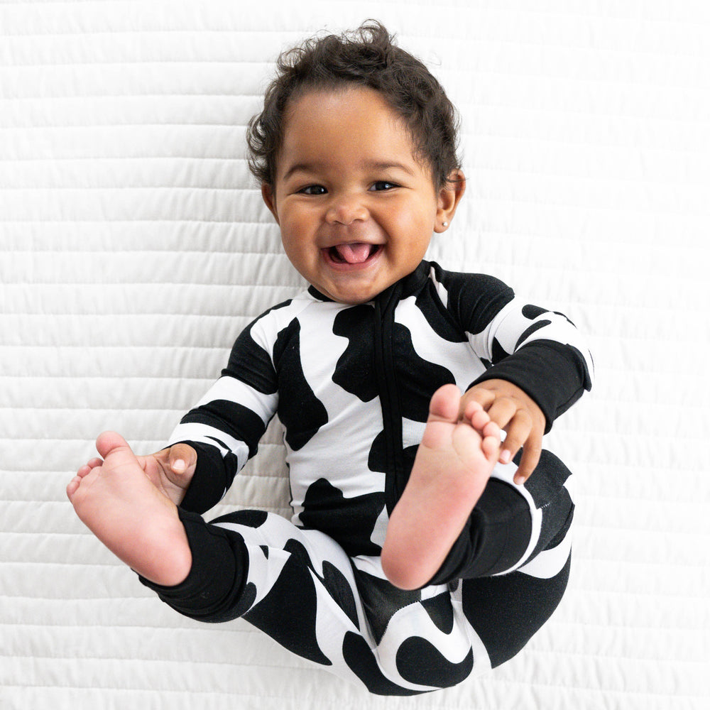 Top view image of baby laying down while wearing the Moo Crew Zippy