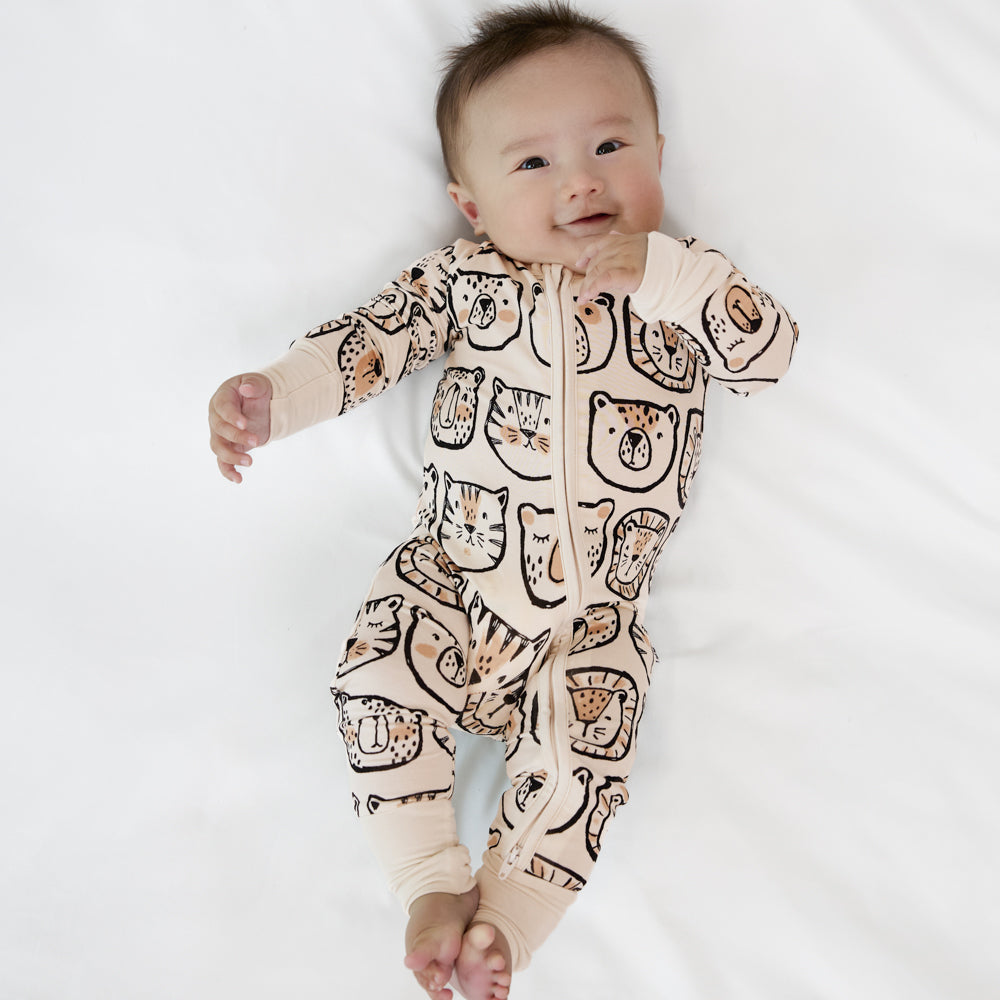 Image of a child laying on a bed wearing a Lions, Tigers, and Bears zippy