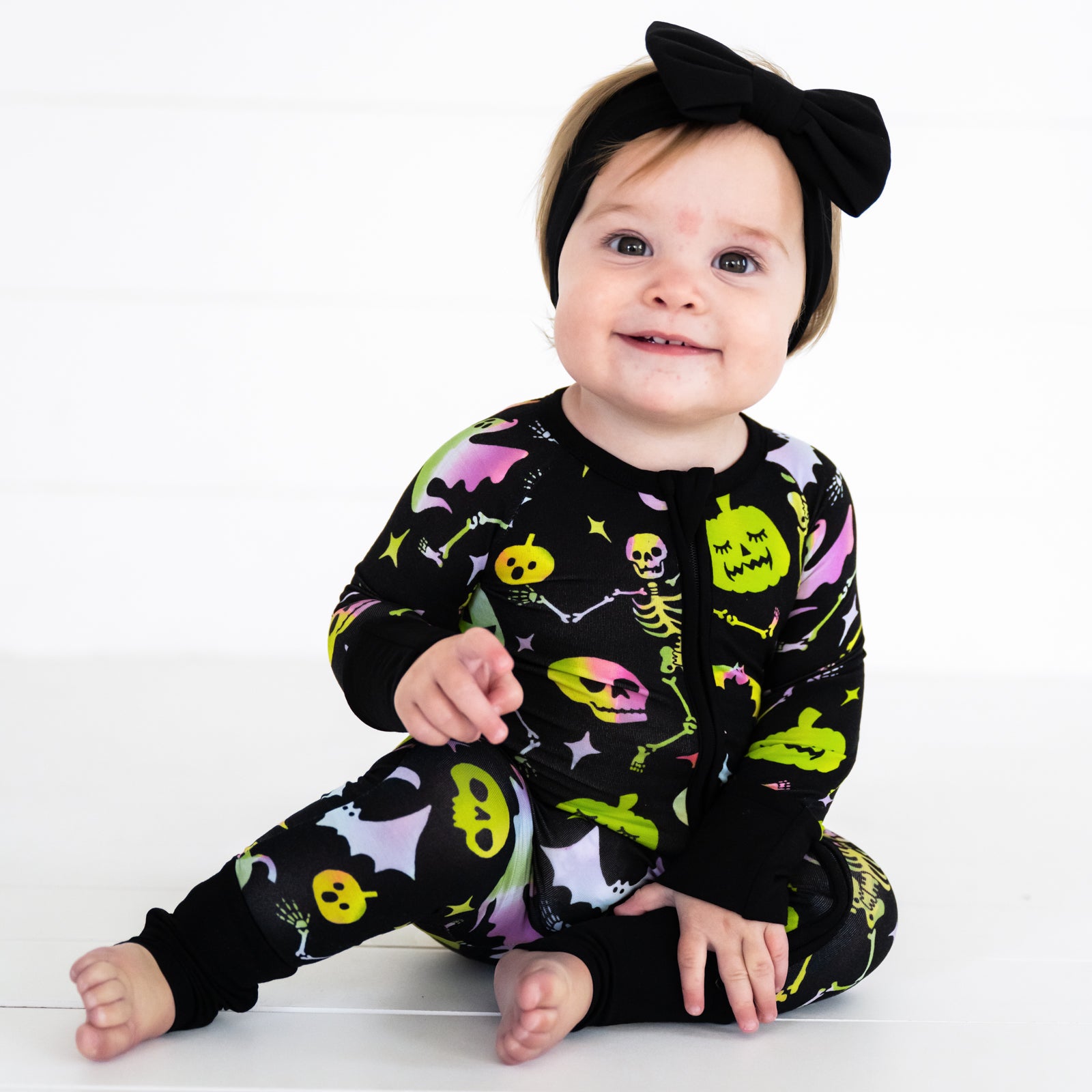 Child wearing a Cool Ghouls zippy paired with a black luxe bow headband