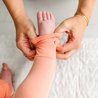 Mother folding over the foot cuff on her child wearing a Peach zippy