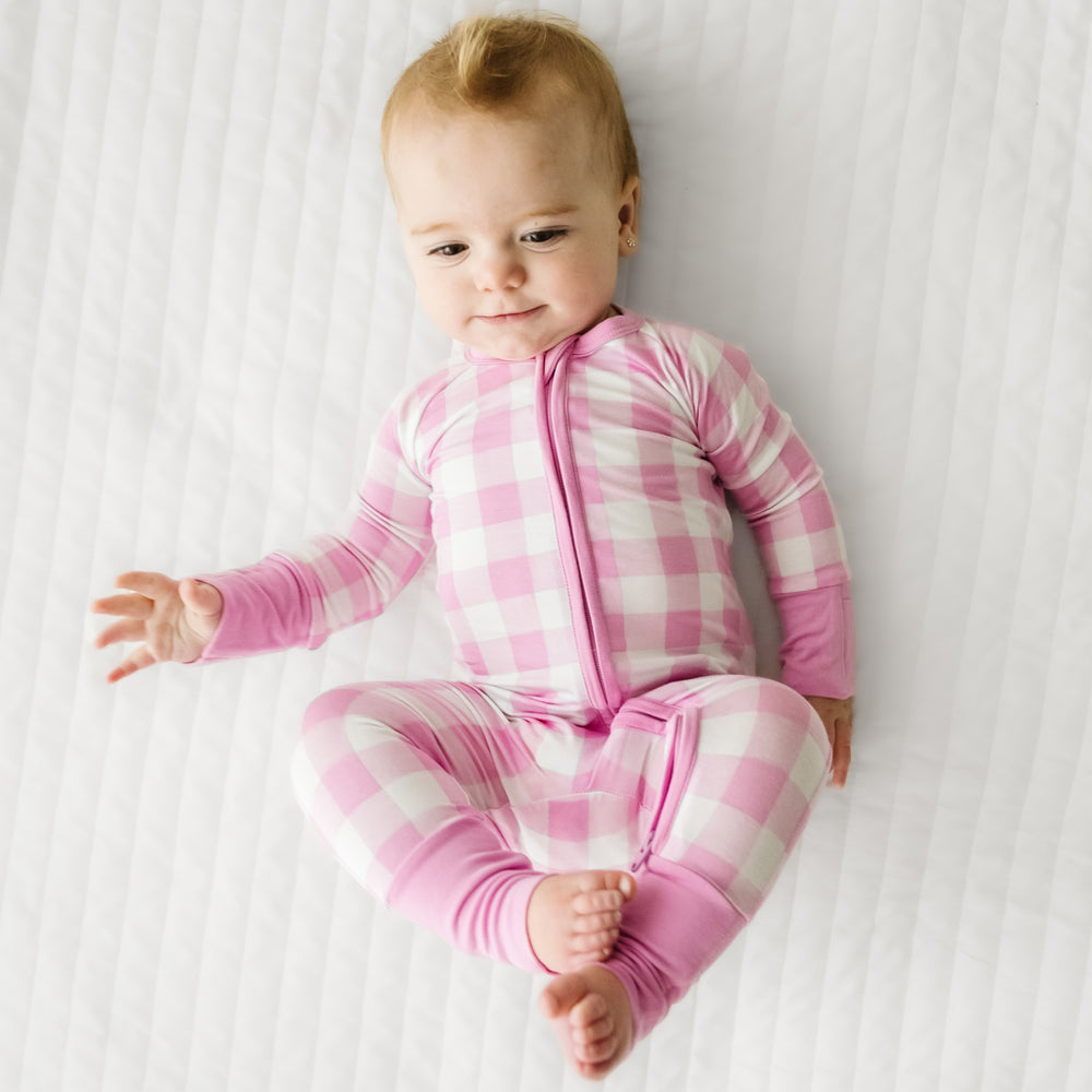 Click to see full screen - Child laying on a bed wearing a Pink Gingham zippy