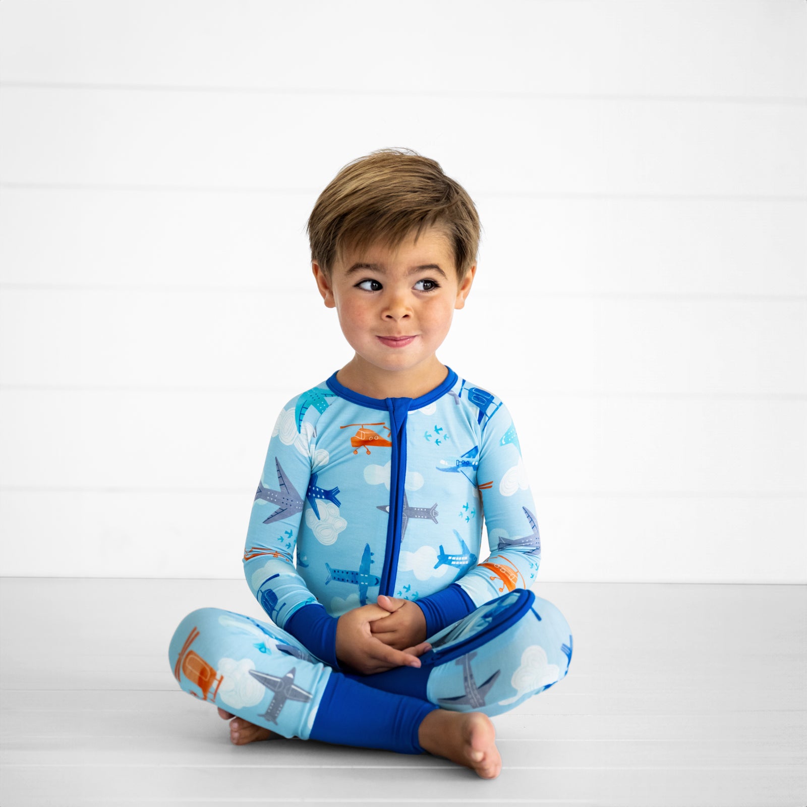 child sitting and posing wearing a Let's Fly zippy