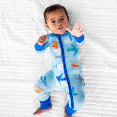 child laying on a bed wearing a Let's Fly zippy