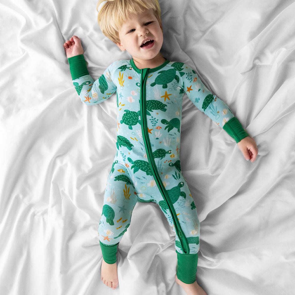 Child laying on a bed wearing a Sea Turtle Friends zippy