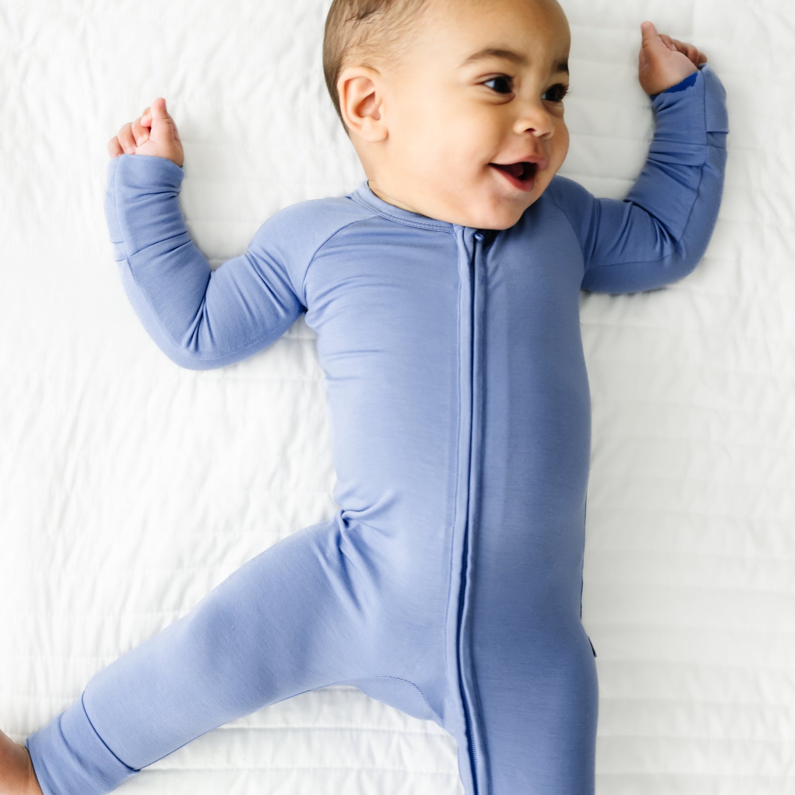 Child laying on a bed wearing a Slate Blue zippy