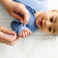 Mother folding over a mitten cuff on their child. Child is wearing a Slate Blue zippy