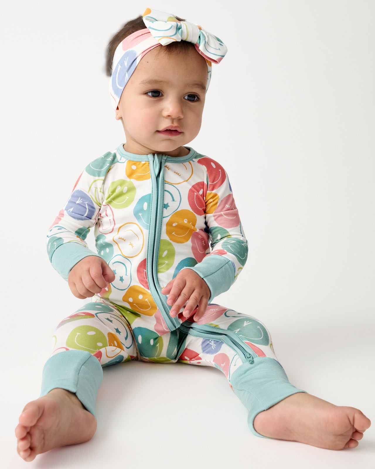 Sitting baby wearing the Positive Vibes Zippy and Luxe Bow Headband