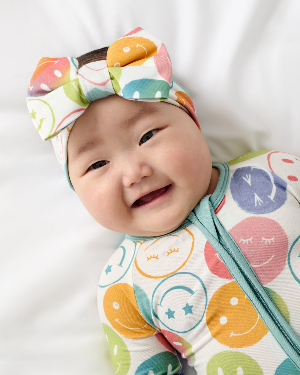 Close up of baby wearing the Positive Vibes Luxe Bow Headband and Zippy