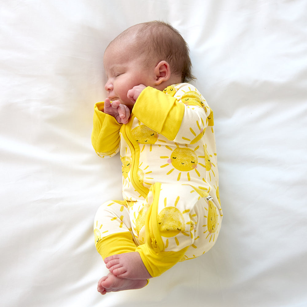 newborn baby scrunched up wearing a sunshine zippy