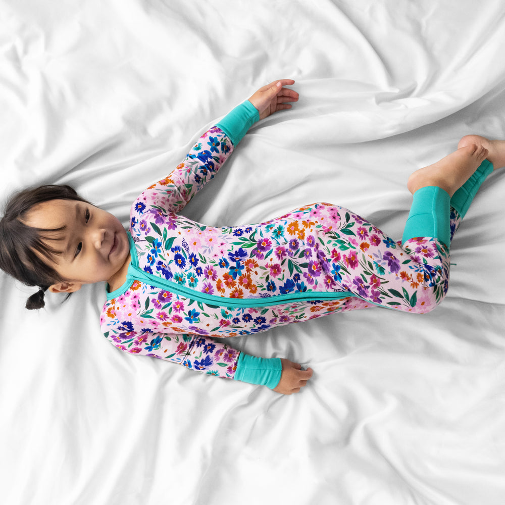 Image of a child laying on a bed wearing a Sweet Pea Floral zippy