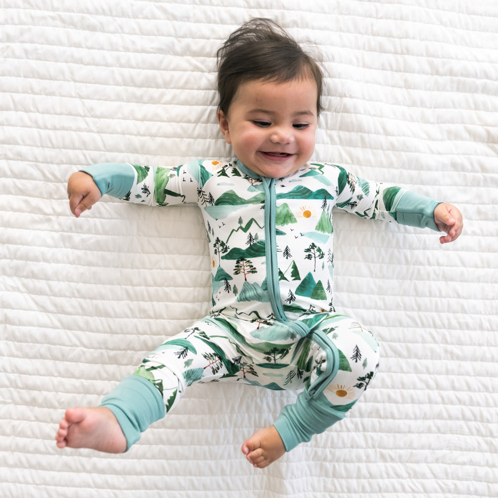 Child laying on a bed wearing a Mountain Mist zippy